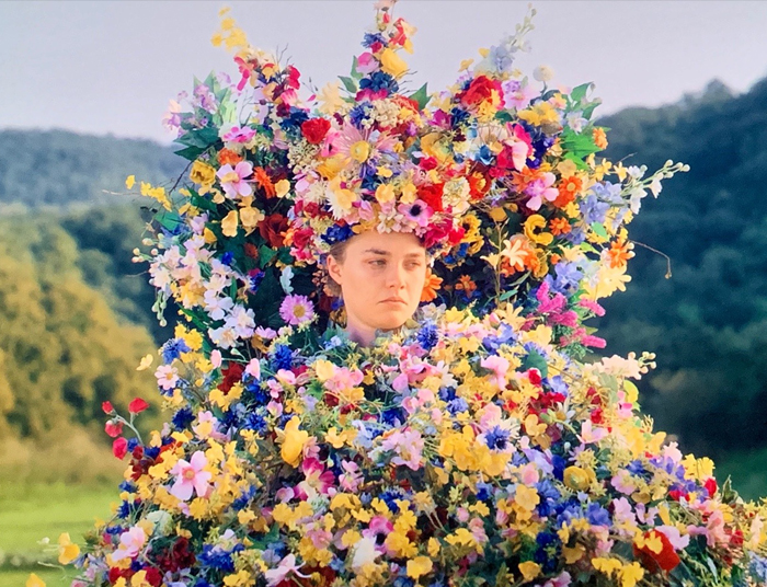 Midsommar, character Dani (Florence Pugh) sadly looks on while adorning a floral dress
